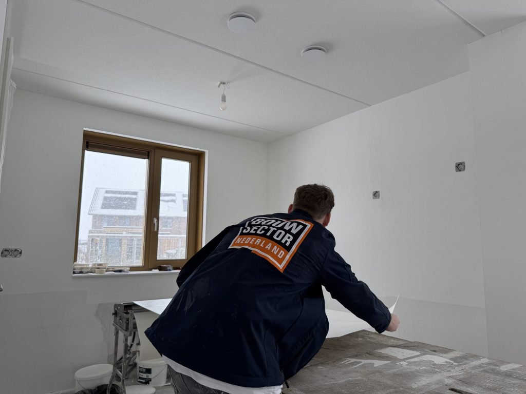 Behanger van Bouwsector Nederland werkt aan de plaktafel in een kamer met gipsplaatplafond